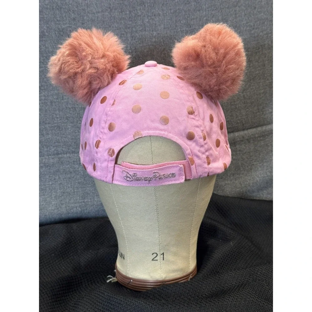Pink polka-dot cap topped with two fluffy faux fur pom poms